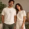 Um casal sorrindo, ele e ela vestindo a camisa marfim do 8º VIRaSER com a estampa no peito